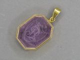 un gros plan d'un pendentif plaqué or orné d'une pierre violette