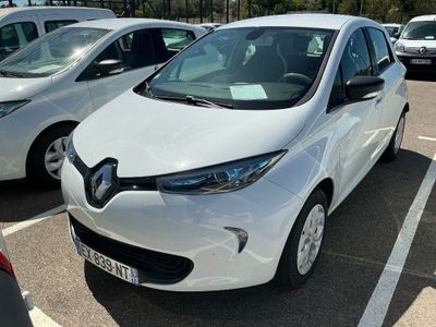 une voiture blanche garée sur un parking, avec d'autres voitures en arrière-plan