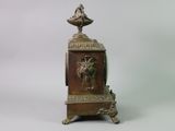 a small bronze clock with a bird on top of it
