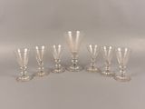 six verres à pied en verre transparent bordés d'argent, posés sur un support blanc