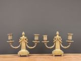 three brass candlesticks on a wooden table against a gray wall