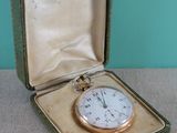 une montre de poche en or dans un écrin posé sur une table
