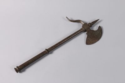 une vieille hache en métal avec un long manche, posée sur une surface blanche
