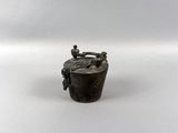 a small metal container with a handle on a white surface