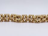 a close up of a gold bracelet on a white surface
