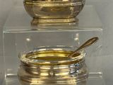 two bowls and spoons sitting on a clear shelf