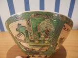 a hand holding a green and white bowl on a table