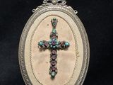 an oval silver locke with a cross in the center of it