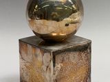 a metal ball sitting on top of a wooden block