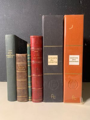 Plusieurs vieux livres sont alignés sur une étagère devant un mur noir
