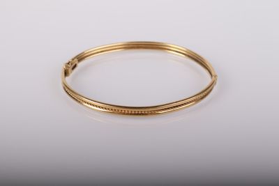 gros plan d'un bracelet en or sur une surface blanche