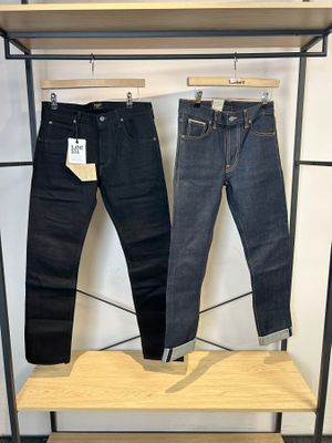 deux paires de jeans suspendues à un portant dans un magasin de vêtements