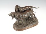 bronze statue of two dogs on a wooden base with a white background