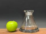 a green apple next to a glass bottle on a wooden table