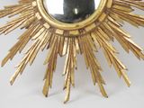 a gold starburst shaped mirror with a person taking a picture