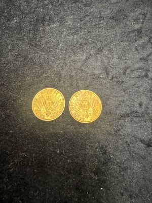 two gold coins sitting on top of a black surface