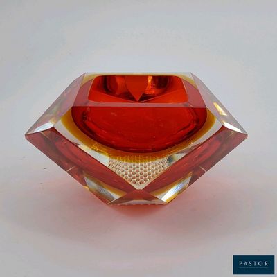 un vase en verre rouge posé sur une surface blanche