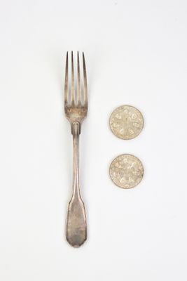 a silver fork and a coin on a white surface