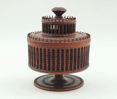 un petit gâteau en bois posé sur un socle, sur fond blanc