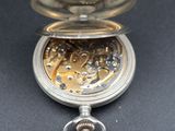 a silver pocket watch with a chain on a black surface