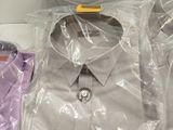 three shirts wrapped in plastic on a table