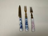 three forks and a knife sitting next to each other on a table