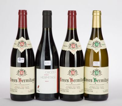 quatre bouteilles de vin sont alignées sur une surface blanche
