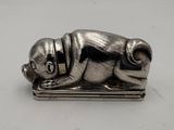 a silver figurine of a dog laying on top of a book
