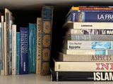 many books that are stacked on a shelf together