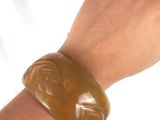 a woman ' s arm with a bracelet that has a carved animal on it