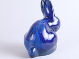 a small blue rabbit figurine sitting on a white surface