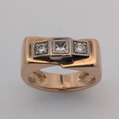 un gros plan d'une bague ornée de trois diamants sur un fond blanc