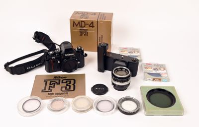 un appareil photo, un objectif, un étui pour appareil photo et une boîte posés sur une surface blanche