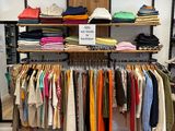 un portemanteau dans un magasin de vêtements, sur lequel est accrochée une pancarte