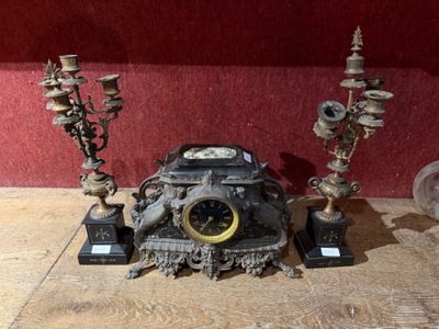 a clock that is sitting on a table next to some candles