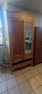 une armoire en bois surmontée d'un miroir, dans une pièce