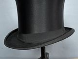 black top hat sitting on a wooden stand on a table