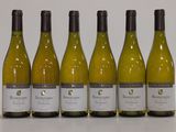 six bottles of white wine lined up in a row on a table
