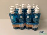 quatre flacons de gel hydroalcoolique posés sur une table blanche