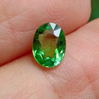 someone is holding a green gemstone in their hand