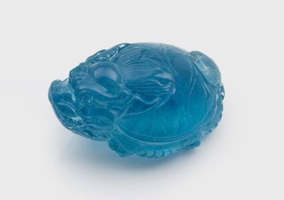 une image représentant une figurine en verre bleue en forme de poisson posée sur une surface blanche