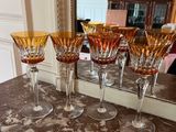 five wine glasses sitting on a counter with a mirror in the background