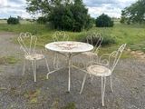 four chairs and a table in the middle of a gravel road