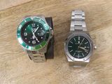two watches sitting on a wooden table next to each other