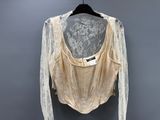 a white blouse hanging on a hanger on a gray wall