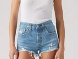 a woman in a white tank top and blue denim shorts
