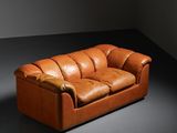 an image of a brown leather couch sitting in a dark room