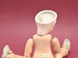 a small doll sitting on the ground with a cup on its head