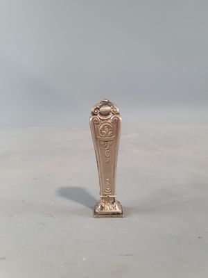 un petit vase en argent posé sur une table blanche