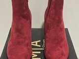 a pair of red sued ankle boots sitting on top of a box